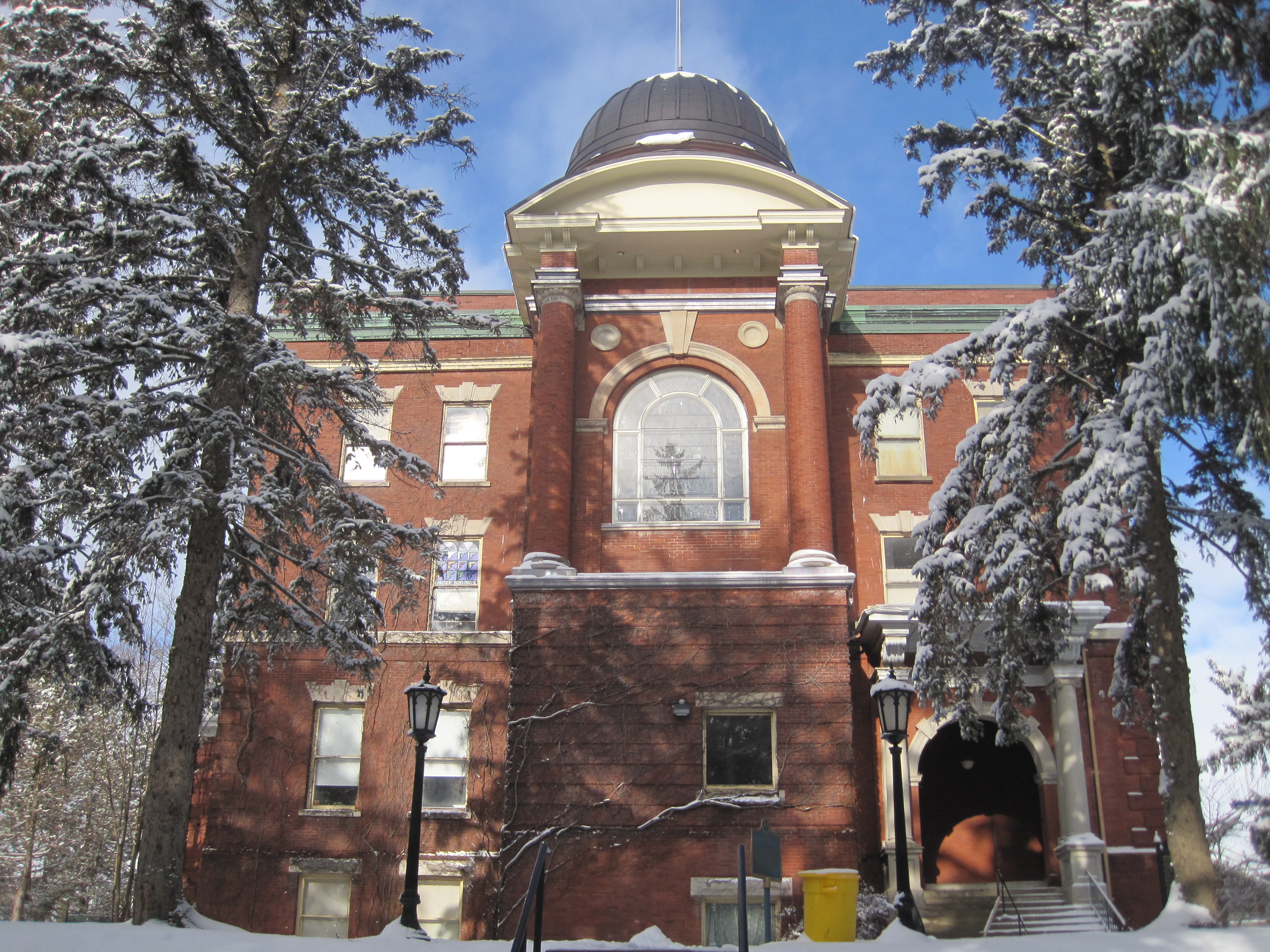 Front facade, three storey red brick Romanesque Revival style building