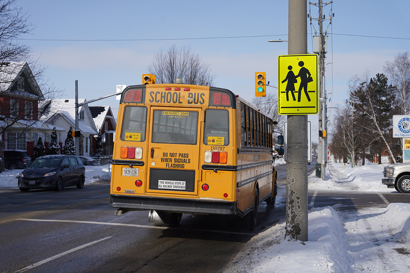 School bus travelling through an intersection, with a yellow school zone sign